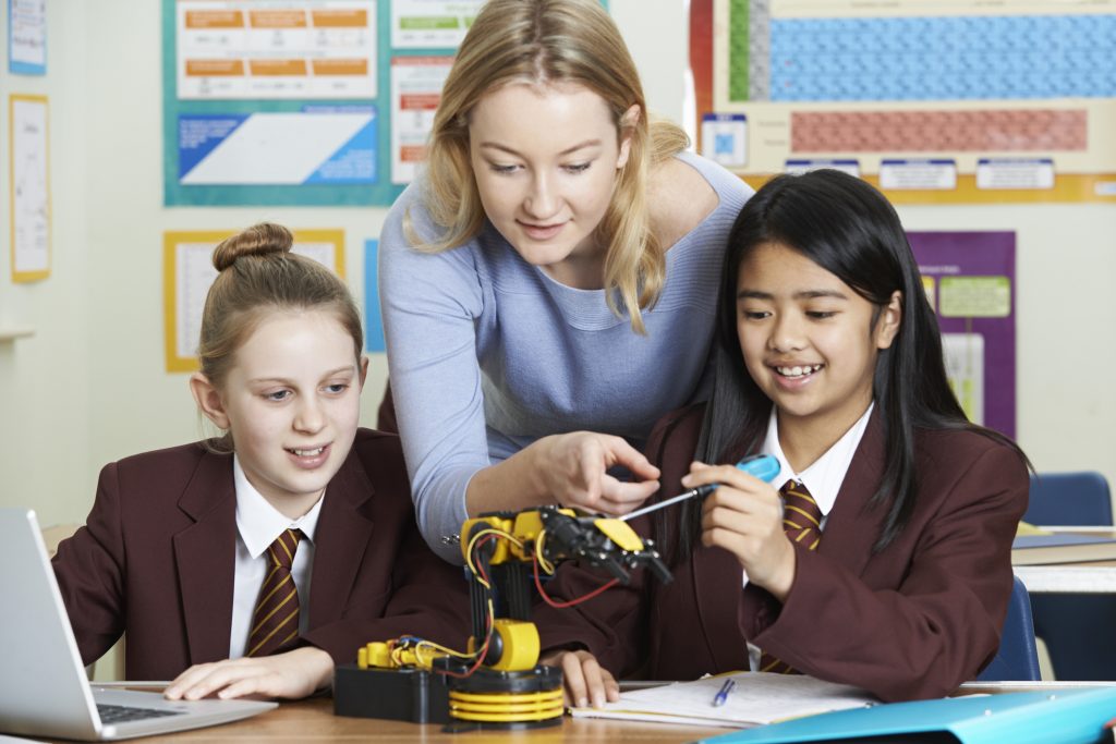 Teacher With Female Pupils In Science Lesson Studying 